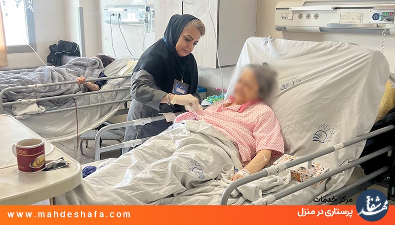 پرستار-مهدشفا-در-حال-اندازه‌گیری-فشار-خون-و-اکسیژن-بیمار-کنار-تخت-در-بیمارستان-شهدای-تجریش